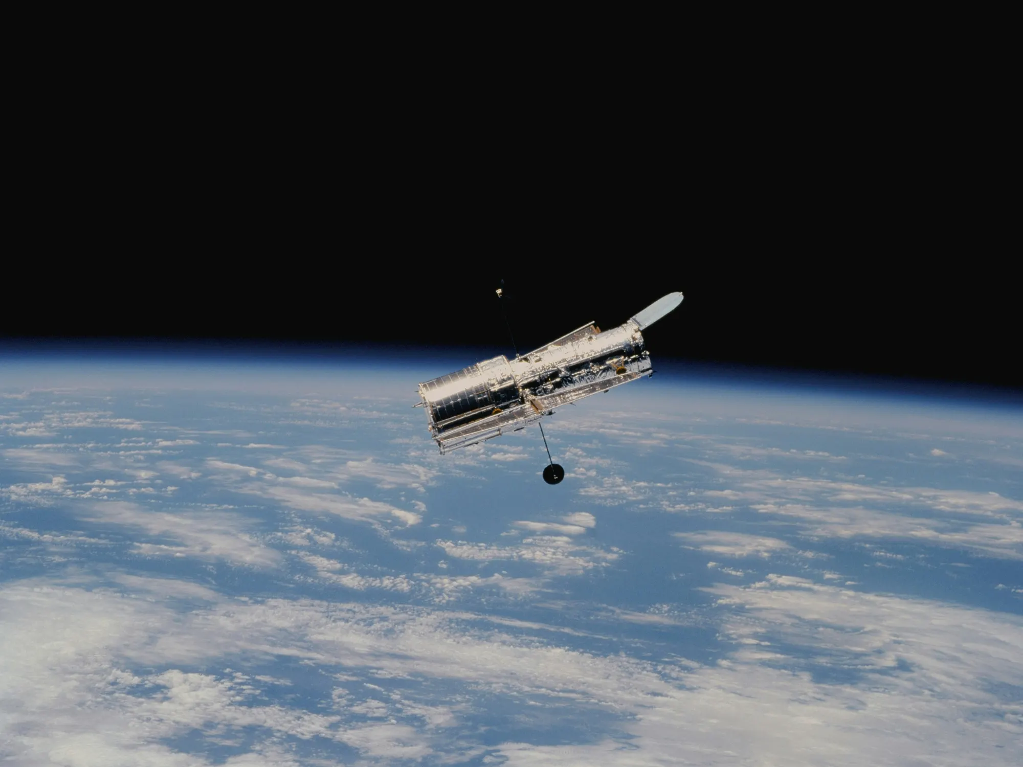 Earth from orbit, clouds over the ocean, a satellite module in the corner